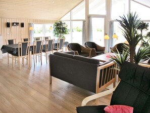 Ett rymligt rum med trägolv, en matplats med bord och stolar samt en sittgrupp med soffa och fåtöljer.