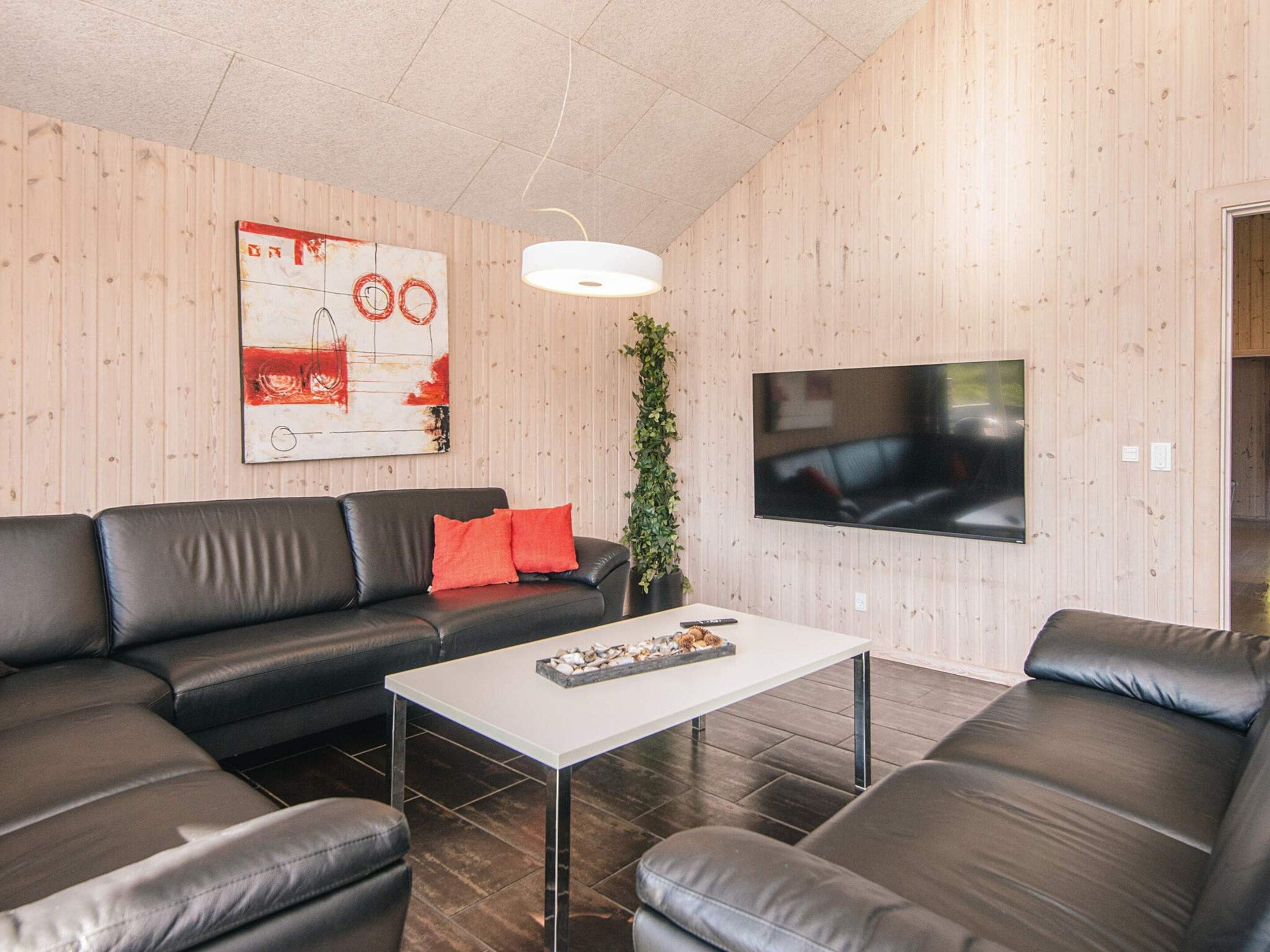 A modern living room with a sectional sofa, a coffee table, a flat-screen TV, and a large abstract painting on the wall.