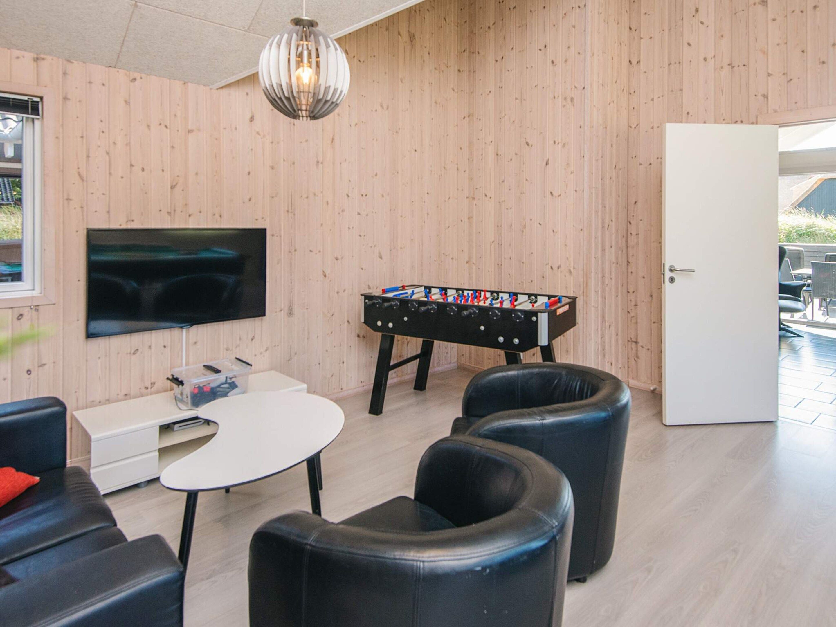 A room with a foosball table, a TV, and leather seating.