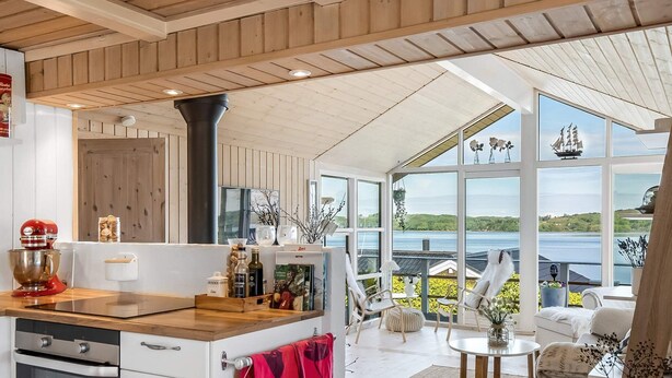 A modern kitchen with a large island, wooden ceiling, and large windows overlooking a scenic view. - 4 Star Holiday Home in Borkop (Borkop)