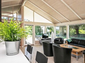 A spacious indoor area with a large potted plant, modern furniture, and large windows offering views of the outdoors. - 4 Star Holiday Home in Hjorring (Hjørring)