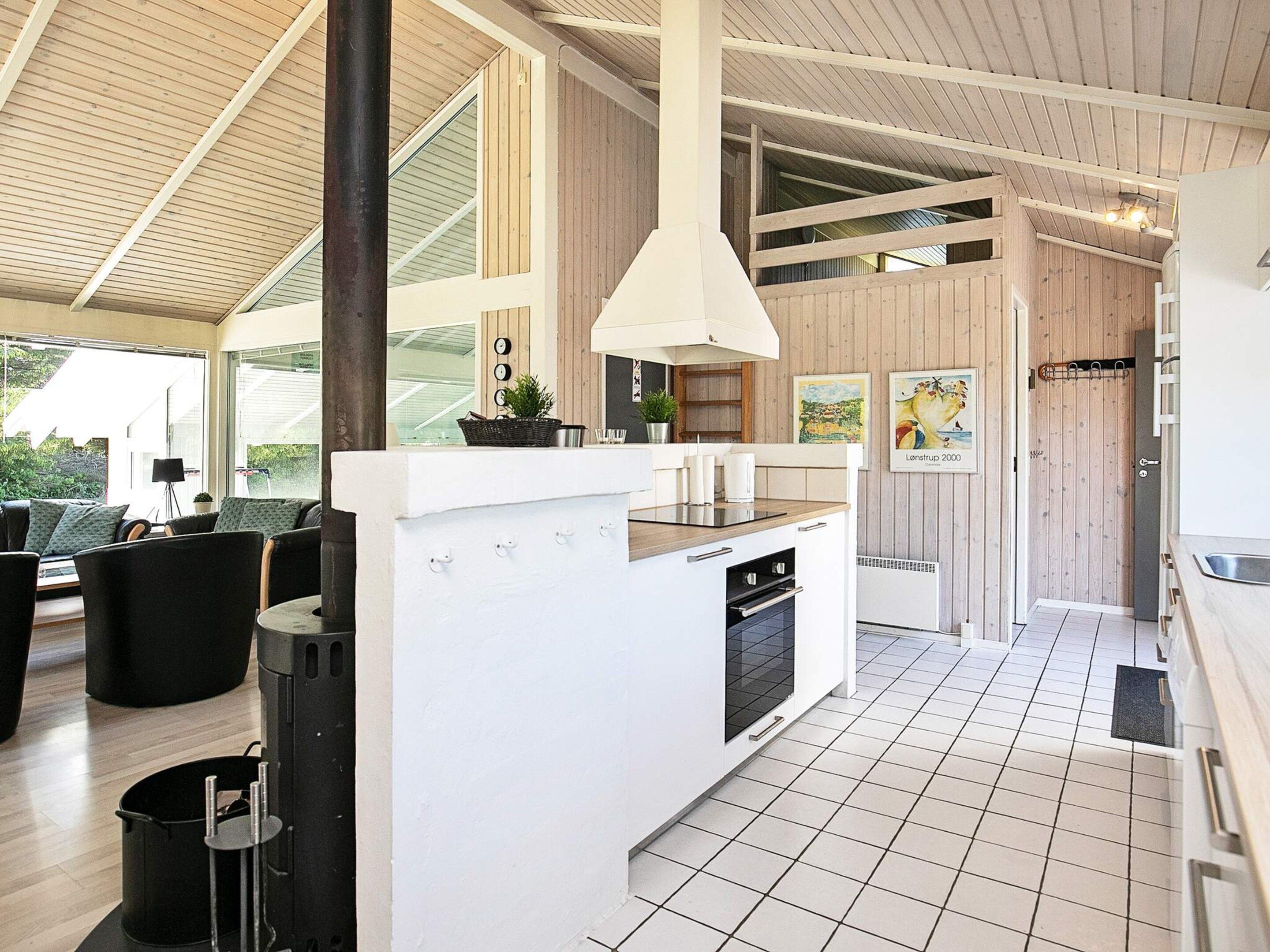 A modern kitchen with a central island, white cabinetry, and a large window.