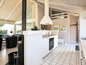 A modern kitchen with a central island, white cabinetry, and a large window.