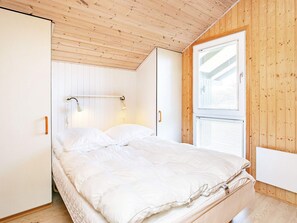 A bedroom with a bed, bedside lamps, a window, and wooden walls. - 4 Star Holiday Home in Lokken (Lokken)
