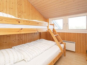 A bunk bed room with wooden walls and a window.