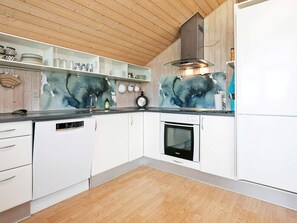 A modern kitchen with white cabinetry, a dishwasher, an oven, and a large abstract painting on the wall.