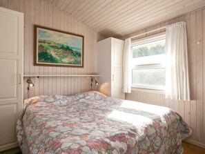 A bedroom with a bed, a painting on the wall, and a window with curtains. - 5 Star Holiday Home in Lokken (Lokken)