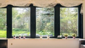 Una stanza con ampie finestre, un soffitto bianco e un pavimento in legno.