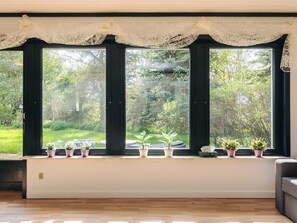 A room with large windows, a white ceiling, and a wooden floor.