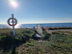 A beach with a lifebuoy sign, a wooden walkway, and a clear view of the sea. - 6 Person Holiday Home in Gedser (Gedser)