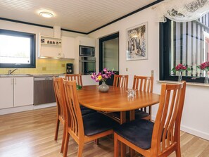 A dining area with a wooden table, chairs, and a vase of flowers.