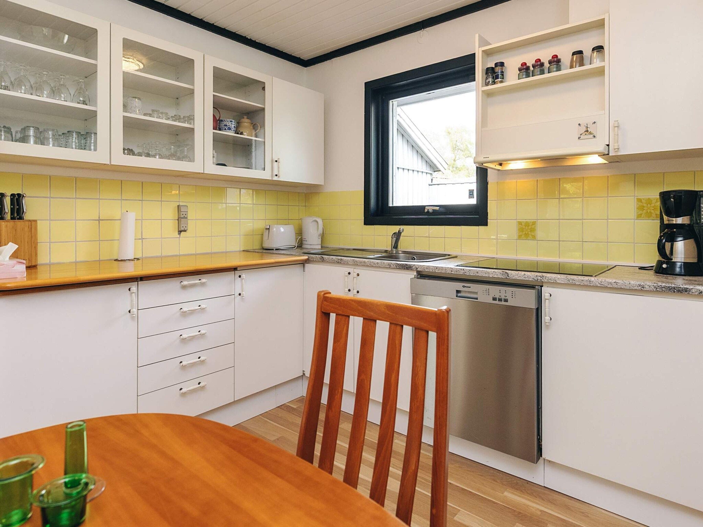 A kitchen with white cabinets, a wooden table, and a window above the sink.
