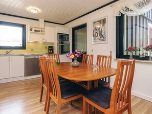 A modern kitchen with white cabinets, a dining table with chairs, and a window with a view.