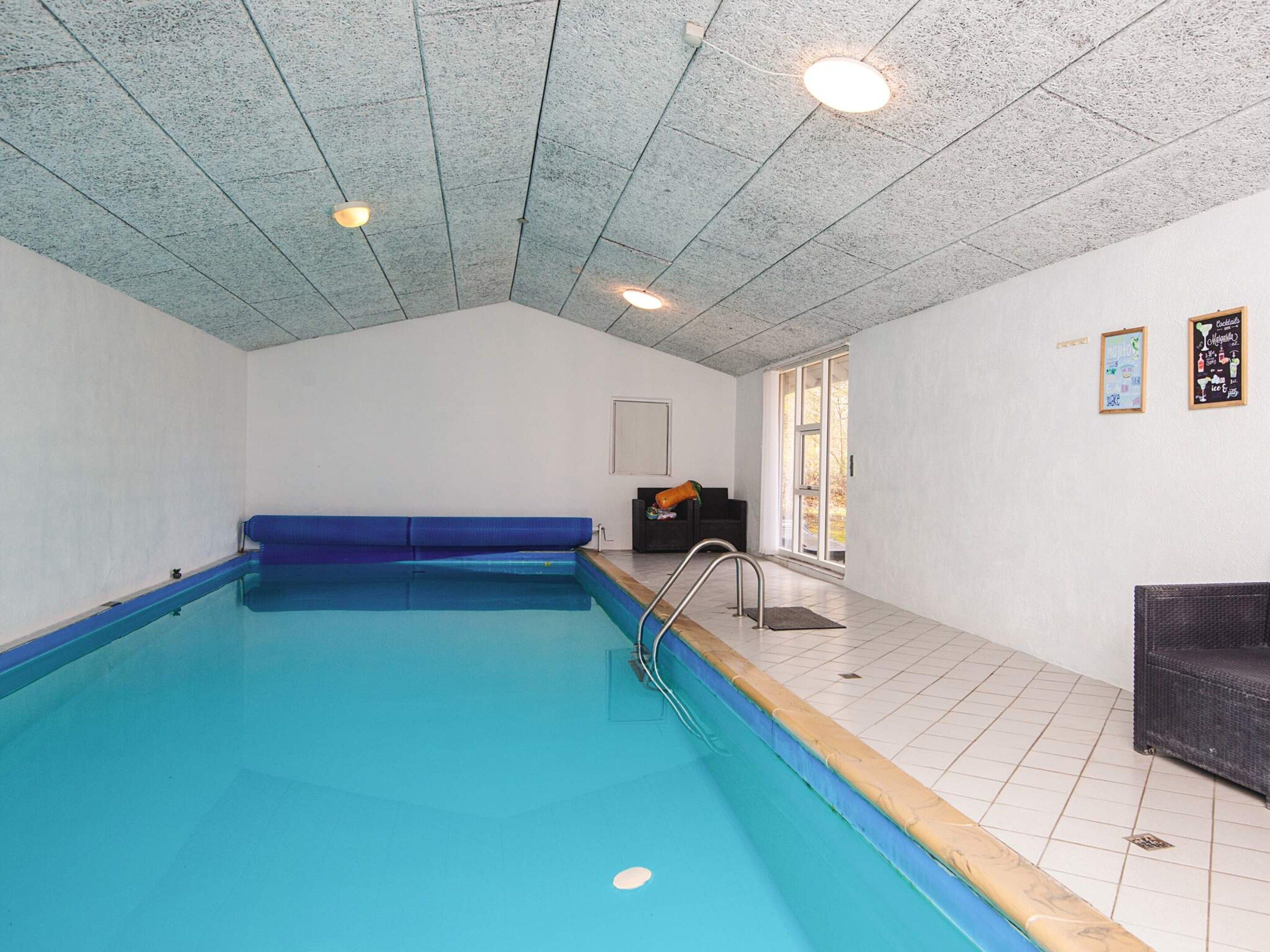 En swimmingpool med blå kant, en bænk og en dør der fører ud.