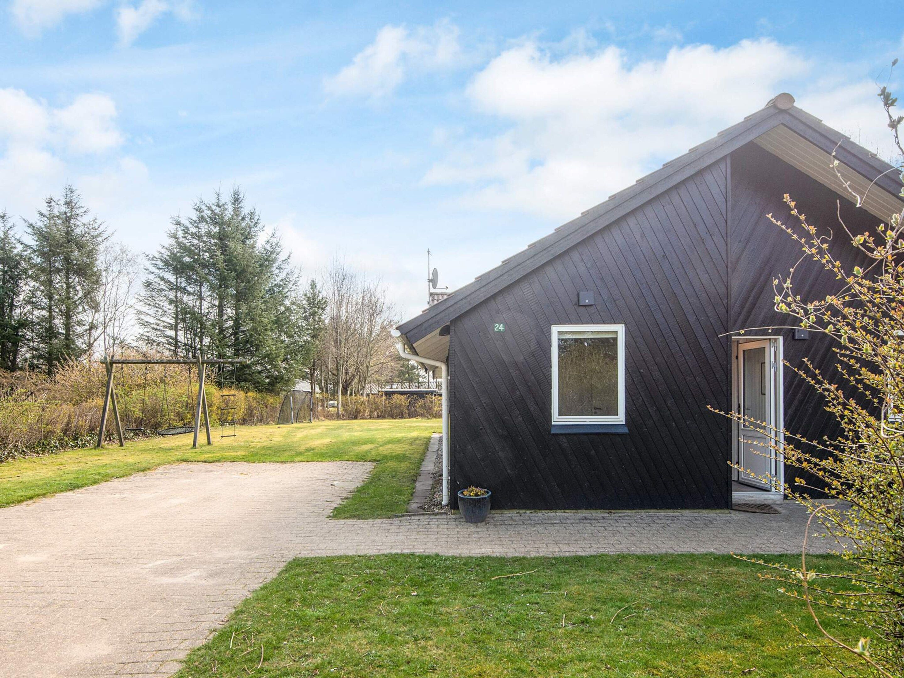 Et moderne hus med mørkt ydre, en belagt indkørsel og en græsplæne.