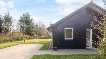 Et moderne hus med mørkt ydre, en belagt indkørsel og en græsplæne.