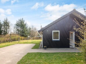 A modern house with a dark exterior, a paved driveway, and a grassy yard.