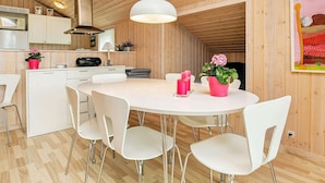 A modern kitchen with wooden walls, a white dining table, and chairs.