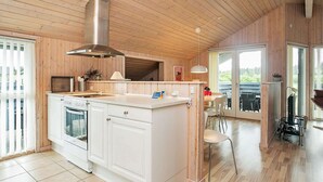 A modern kitchen with wooden ceiling and cabinetry, a central island, and a large window.