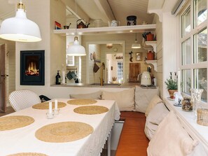 A cozy dining area with a table set for two, a fireplace, and a kitchen visible through an archway. - 6 Person Holiday Home in Jerup (Jerup)