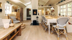 A cozy, well-lit dining area with a long wooden table, wicker chairs, and a white tablecloth. - 6 Person Holiday Home in Jerup (Jerup)