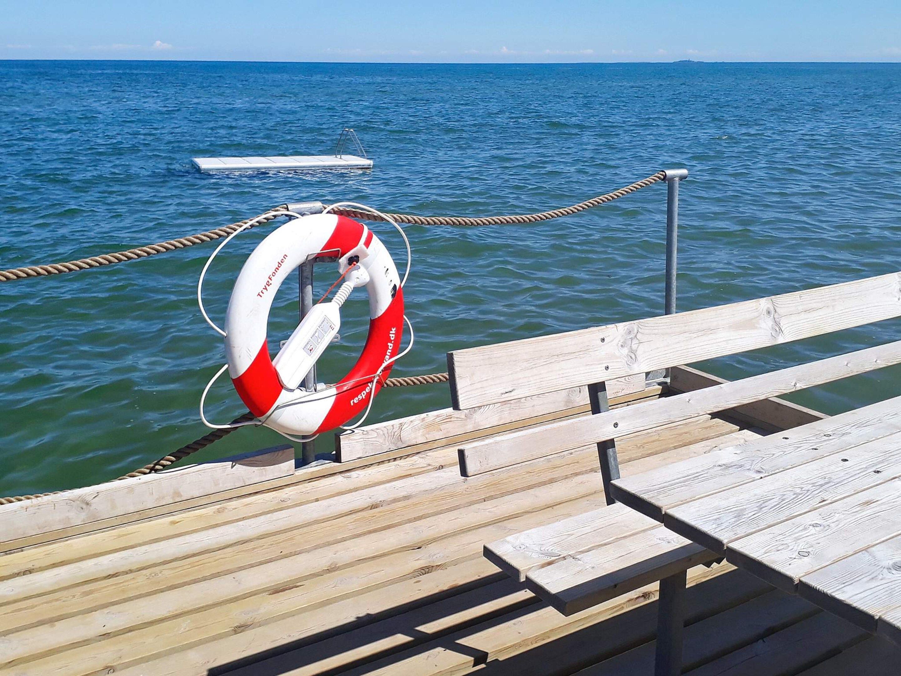 A wooden pier with a lifebuoy attached to a rope.