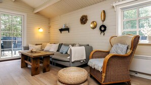 A cozy room with a wooden ceiling, a grey sofa, a wicker chair, a wooden table, and wicker ottomans. - 6 Person Holiday Home in Jerup (Jerup)