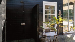 A wooden deck with a black exterior wall, a white door, and a small potted plant. - 6 Person Holiday Home in Jerup (Jerup)