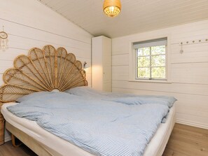 A bed with a woven headboard, a window with blinds, and a wall-mounted light fixture. - 6 Person Holiday Home in Jerup (Jerup)