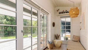A bright, open room with large windows, a wooden bench, a woven rug, and a hanging light fixture. - 6 Person Holiday Home in Jerup (Jerup)
