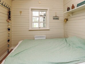 A room with a bed, a window, and a wall-mounted shelf with decorative items.