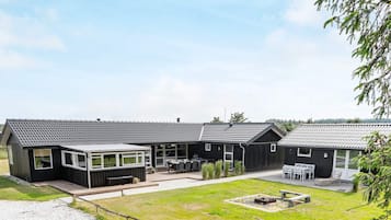 Uma fileira de edifícios modernos, com cores escuras, telhados planos, áreas de estar ao ar livre e um pátio gramado.