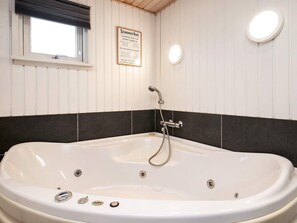 A bathroom with a freestanding bathtub, a window, and a sign on the wall.