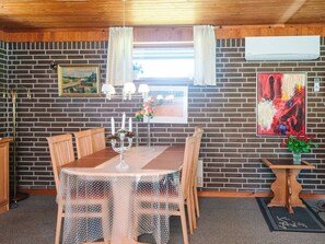 A dining area with a brick wall, a table with chairs, a candelabra, and artwork. - Cozy Holiday Home in Henne near Sea (Henne)