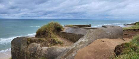 A coastal landscape with a concrete structure, possibly a fortification, overlooking the sea.