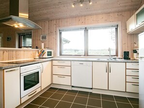 A modern kitchen with a large window, white cabinetry, and a tiled floor. - 4 Star Holiday Home in Lokken (Lokken)