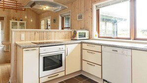 A kitchen with wooden paneling, a built-in oven, a microwave, and a dishwasher. - 4 Star Holiday Home in Lokken (Lokken)