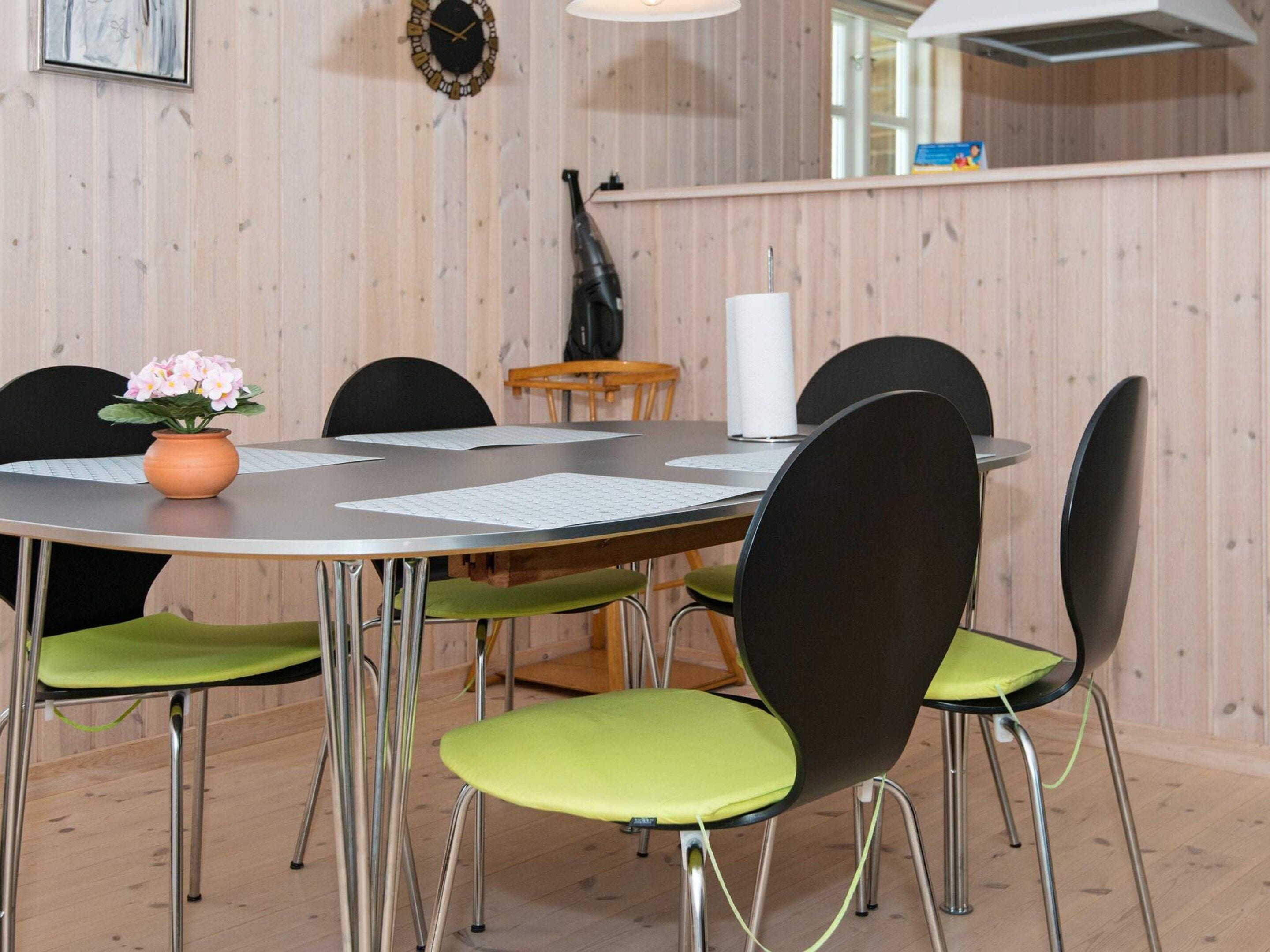 A round dining table with four chairs, a vase with flowers, and papers on the table.