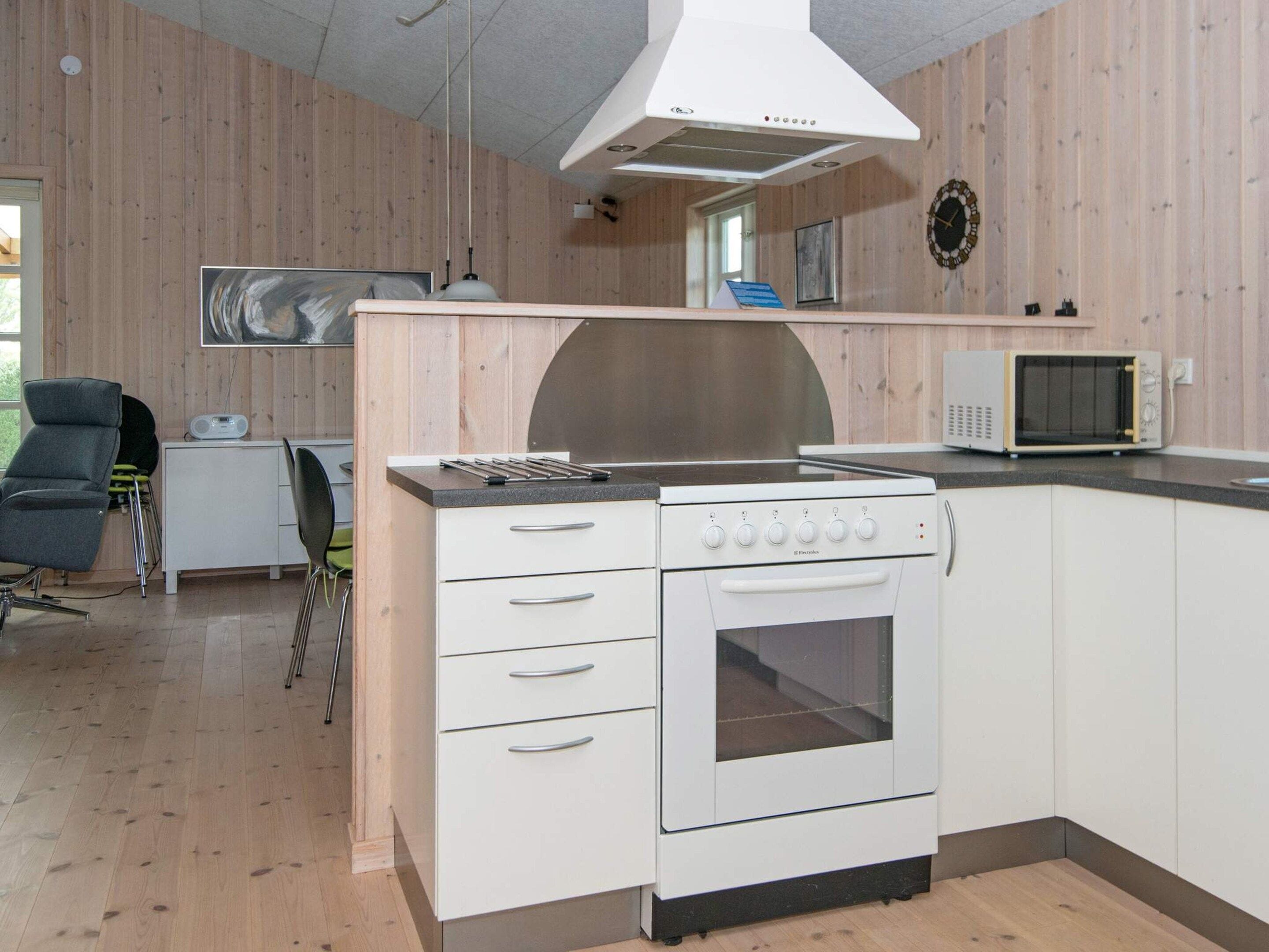 Une cuisine moderne équipée d’un four encastré, d’un four à micro-ondes et d’une grande fenêtre au-dessus de l’évier.