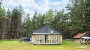 Ett envåningshus med en stor glasfasad, en skorsten och ett litet garage som är sammanbyggt med huset.