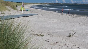 A sandy beach with a clear sky, a few people, and a surfboard. - 6 Person Holiday Home in Albaek-by Traum (Aalbaek)