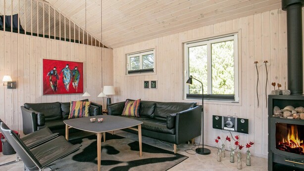 A modern living room with a fireplace, leather sofas, a coffee table, and a large window. - 4 Star Holiday Home in Blavand (Blavand)