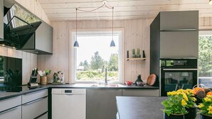 A modern kitchen with a dishwasher, built-in oven, and a window with a view of greenery. - 4 Star Holiday Home in Blavand (Blavand)