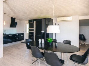 A modern kitchen with black cabinets, a central island, and a dining area with a round table and chairs.