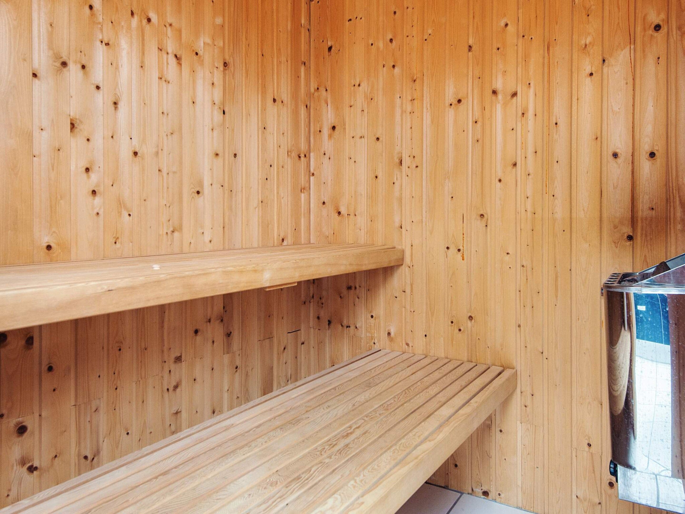 A wooden sauna with two benches and a metal sauna heater.