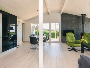 A modern interior with a dining area, a fireplace, and a view of the outdoors. - Holiday Home in Hejls (Hejls)