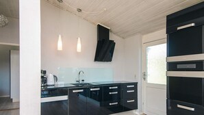 A modern kitchen with black cabinets, a stainless steel sink, and pendant lighting. - Holiday Home in Hejls (Hejls)