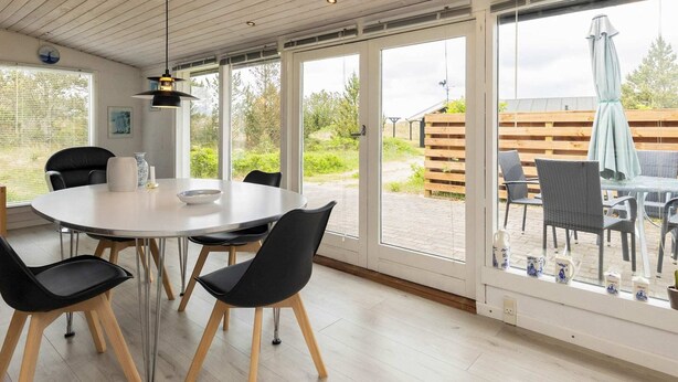 A modern dining area with a round table, black chairs, and a pendant light. - Spacious Holiday Home in Strøby near Beach (Aalbaek)
