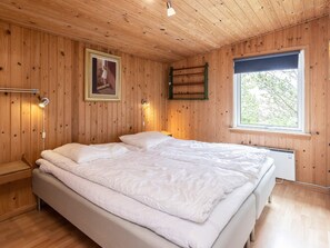 A wooden-paneled bedroom with a bed, bedside lamps, a framed picture, and a window. - Spacious Holiday Home in Strøby near Beach (Aalbaek)