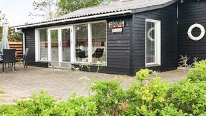 A small, dark wooden building with a covered patio area, large windows, and a sign reading "Litrose." - Spacious Holiday Home in Strøby near Beach (Aalbaek)